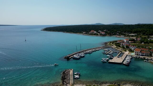 Aerial drone view of a speedboat approaching Silba Island in Croatia across the deep blue Adriatic Sea. Scenic Mediterranean coastline, turquoise waters and a charming island village create an idyllic