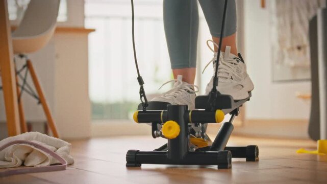 A young girl wearing athletic leggings and sneakers engages in a cardio workout on a stepper in her bright and airy home. This scene embodies a conscious approach to health through regular exercise