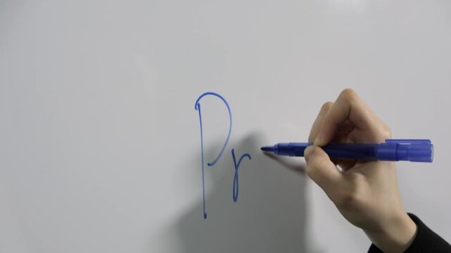Close-up of a girl's hand writing the word 'progress' on a white board with a blue marker