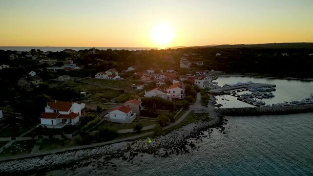A stunning aerial drone shot capturing the warm golden sunset over the Sotorisce bay and Mulj harbor area on Silba Island, Croatia. The perspective showcases the sheltered marina filled with boats