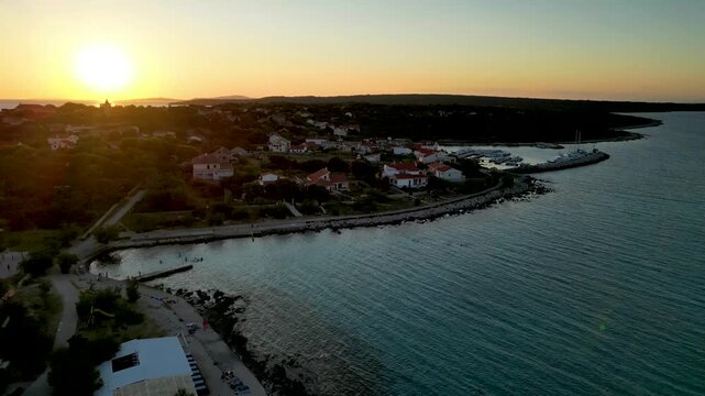 A stunning aerial drone shot capturing the warm golden sunset over the Sotorisce bay and Mulj harbor area on Silba Island, Croatia. The perspective showcases the sheltered marina filled with boats