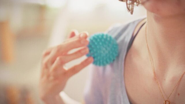 At home, girl performs lymphatic drainage massage using needle ball on her skin, gently rolling tool to boost blood circulation and rejuvenate her complexion, showcasing simple self-care technique