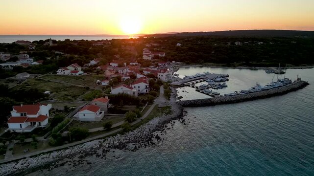 A stunning aerial drone shot capturing the warm golden sunset over the Sotorisce bay and Mulj harbor area on Silba Island, Croatia. The perspective showcases the sheltered marina filled with boats