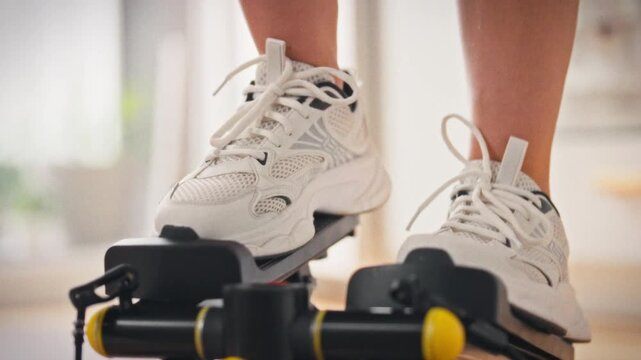Athlete wearing leggings and white sneakers performs a cardio workout on a stepper at home, demonstrating a commitment to an active lifestyle and daily physical activity in a comfortable environment