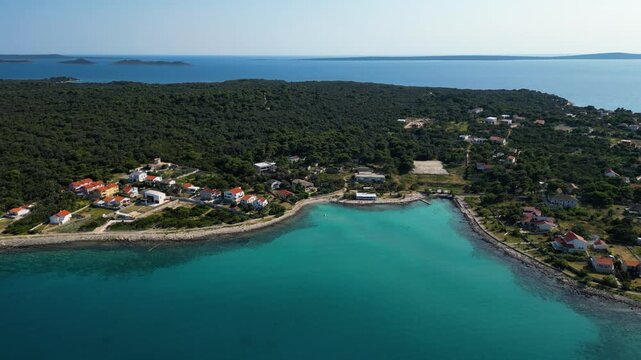Stunning aerial view of Sotorisce Bay on the eastern shore of Silba Island, Croatia, featuring crystal clear turquoise water, a sandy seabed, and a protected harbor filled with white sailboat