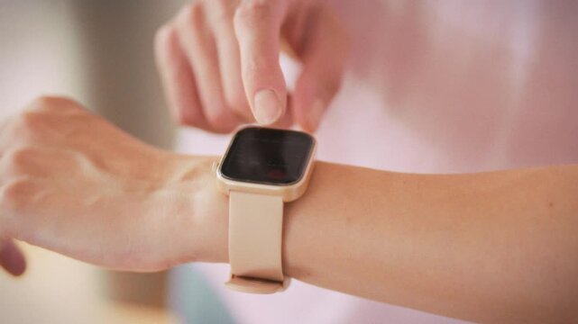 In bustling gym, focused girl glances at her fitness watch, reading health stats that guide her training. The smart device highlights mindful approach to exercise, tracking performance and wellbeing