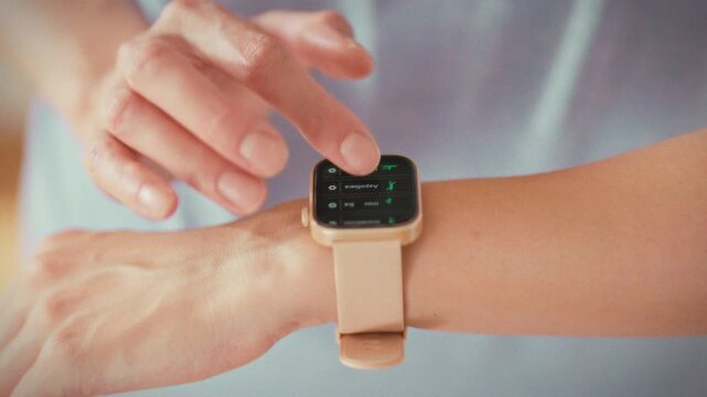 A girl closely examines her fitness watch, analyzing heart rate and calorie data on its screen. This wearable device enables her to track physical activity, embracing modern health monitoring