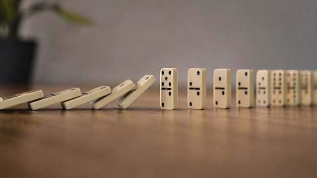interrupted. A chain of falling dominoes interrupted, focusing on the break point. wellbeing guides, coaching materials, designed for coaching and self-improvement content, used by account managers.