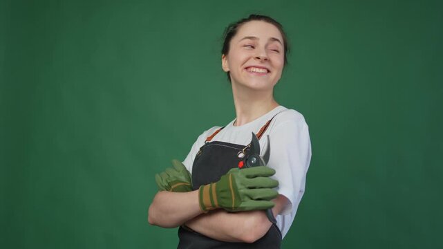 Running of own business. Woman florist gardener farm worker with pruner wearing apron isolated on green background. Happy small business owner working at flower plants shop smiling. Small business