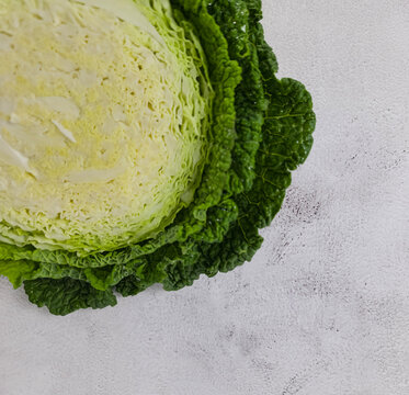 Minimal food background with a half  of fresh Savoy cabbage  on a light concret background.