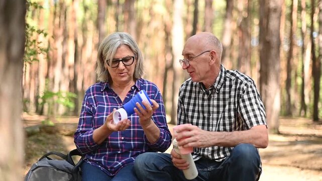 Senior couple using reusable collapsible cup during forest hiking stop video Full HD