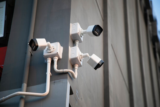 Group of modern CCTV security cameras installed on the corner of a grey concrete building wall.