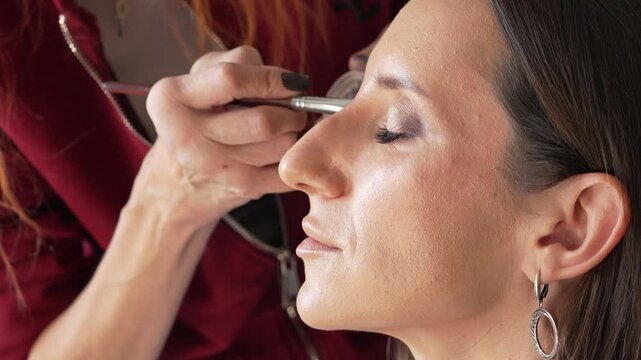 Makeup application beauty woman getting foundation applied by professional artist, close-up profile shot