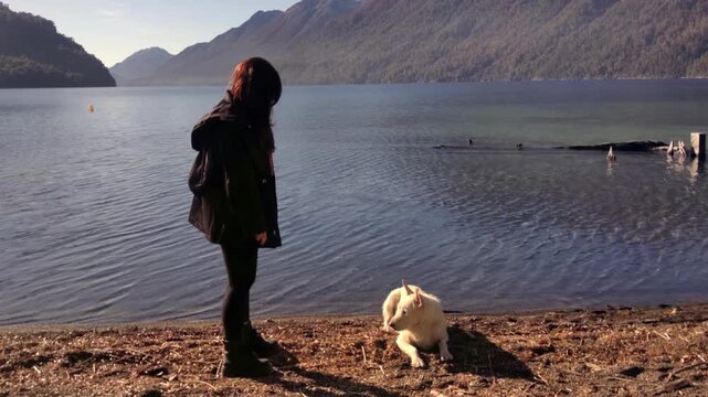 Young Woman Asking Dog for Paw on Shore of Lake Nahuel Huapi in Patagonia 