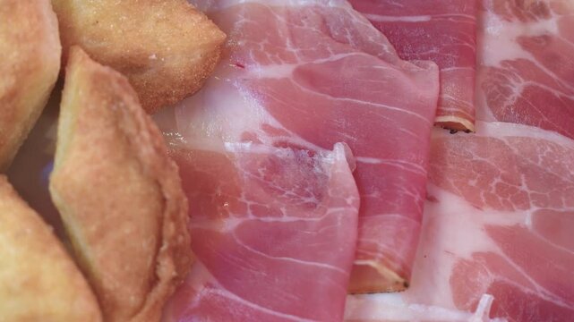 Thinly sliced Tuscan raw ham with pecorino on rustic dish