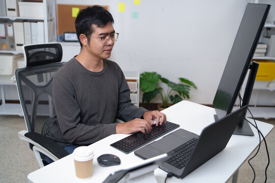 Focused Programmer Working on Computer in Tech Workspace with Multiple Screens