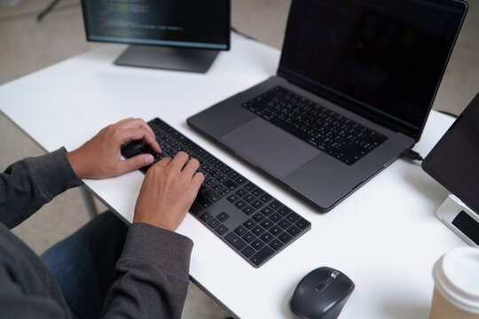 Focused Developer Programming Code on Laptop with Multiple Monitors for Software Development