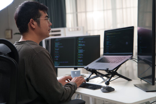 Focused Developer Working on Code with Multiple Computer Screens in a Tech Environment