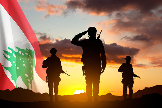 Silhouettes of a soldiers with Lebanon flag against the sunset. National Holidays concept. Armed Force of Lebanon