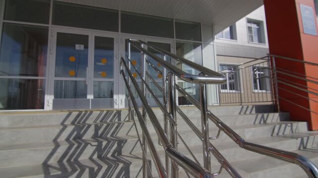 Glossy chrome railings beside glass doors with safety markers. Clean architectural design provides accessible and welcoming environment