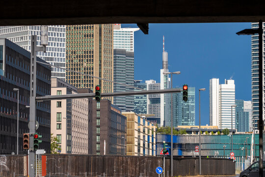 Through a street opening in Frankfurt Bankenviertel, Germany, traffic lights frame the skyline as office towers and urban architecture define the financial district