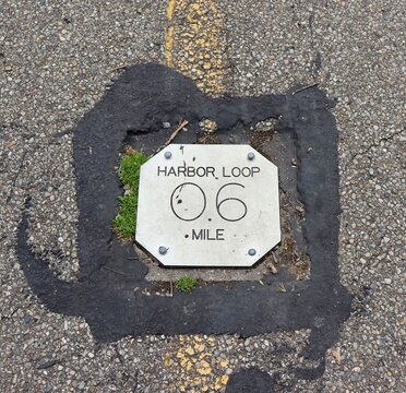 A close view of the metal trail sign on the pavement.