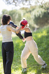 Fototapeta premium Women training boxing outdoors striking a focus mitt