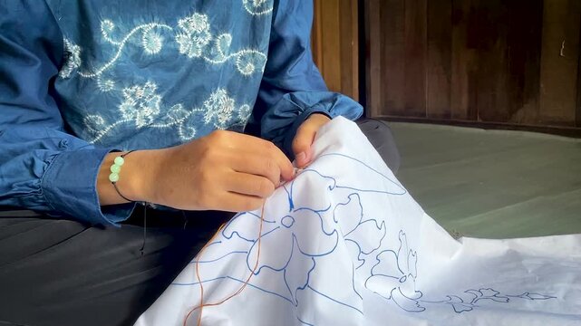 Artisan Hands Stitching Floral Pattern on White Fabric 
for Traditional Tie Dye Textile in Indonesia Workshop