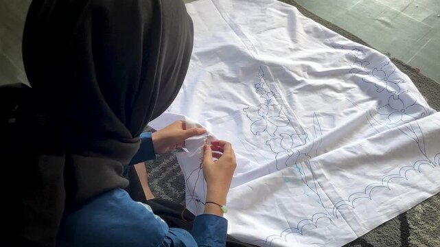 Artisan Hands Stitching Floral Pattern on White Fabric 
for Traditional Tie Dye Textile in Indonesia Workshop