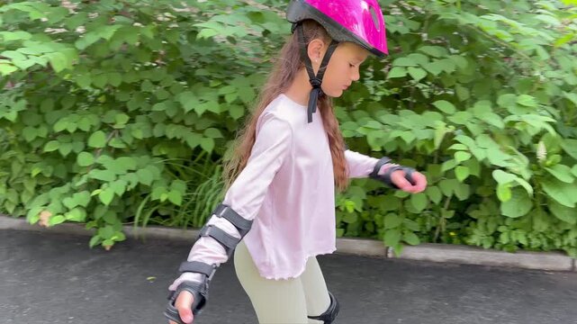 a young girl with long brown hair rollerblading along a paved path outdoors. Roller skating, balance skills