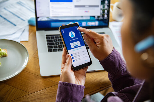 Woman using mobile banking app at home desk