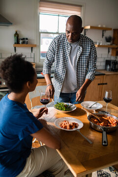 Couple sharing pasta and wine at home kitchen
