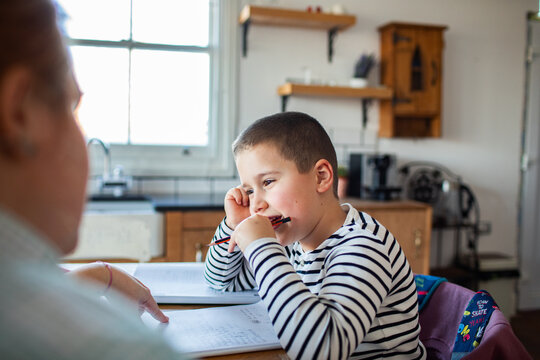 Young boy doing homework with parent at kitchen table