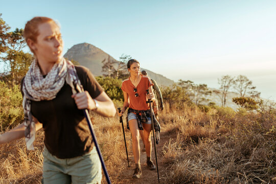 Friends hiking coastal mountain trail at sunset