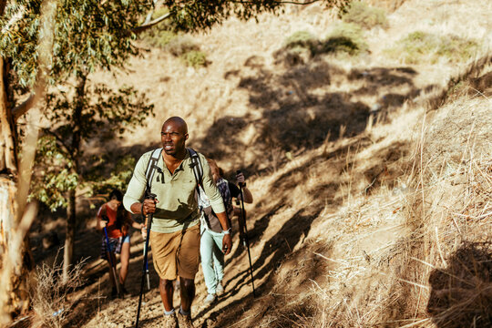 Group of hikers trekking uphill on dry mountain trail