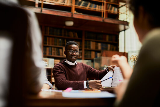 Student presenting notes to classmates in university library