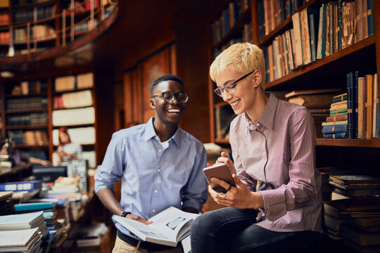 Students collaborating with smartphone in historic library