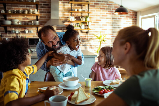 Happy family laughing at breakfast in home kitchen