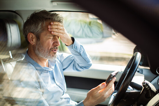 Stressed driver checking smartphone in car interior