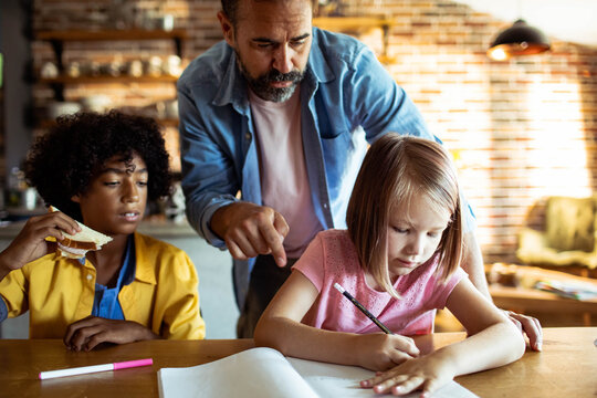 Father helping kids with homework at kitchen table