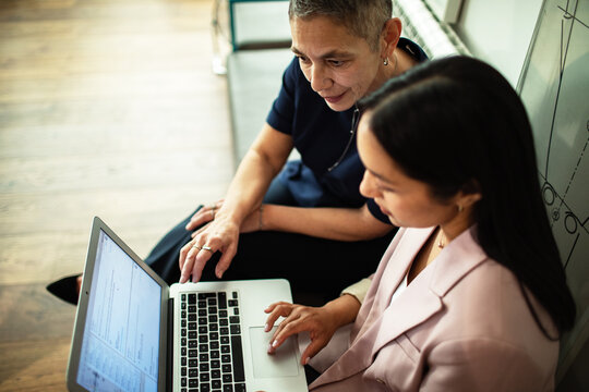 Two businesswomen collaborating on laptop in office