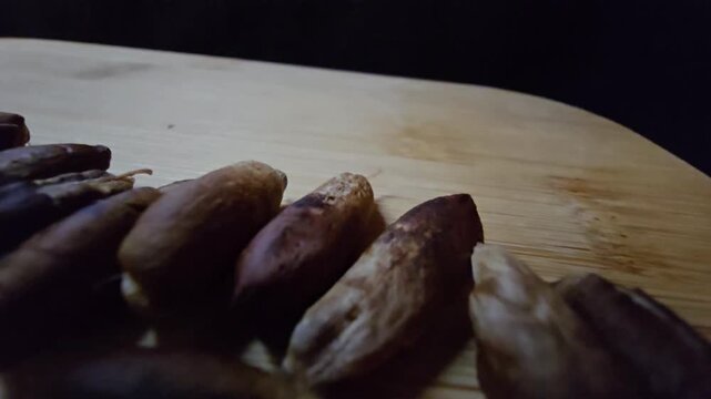 Close-up of dried date pits (seeds) arranged on a wooden board, highlighting the natural textures of palm seeds against a dark background, perfect for organic, agricultural, and culinary concepts.