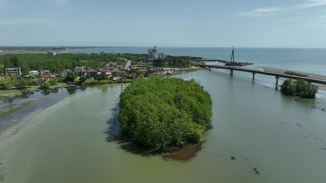 High angle drone shot of Anaklia coastal resort in Georgia, showing the famous pedestrian bridge, green river island, and scenic sea delta landscape.