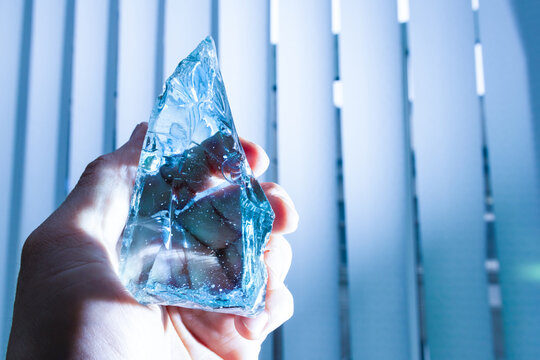 Holding a piece of glass on vertical window blinds background at a laboratory