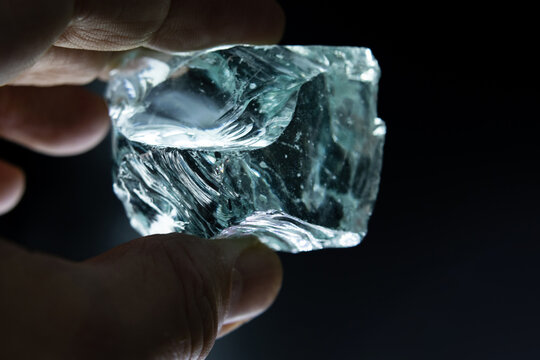 Closeup glass crystal in hand on dark background