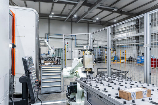 White robotic arm with CNC machinery in modern manufacturing building