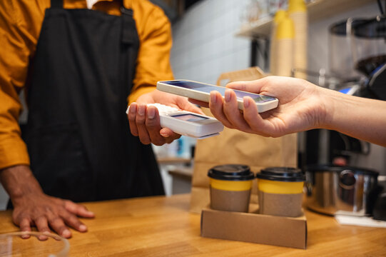 Customer paying for coffee using smart phone at cafe