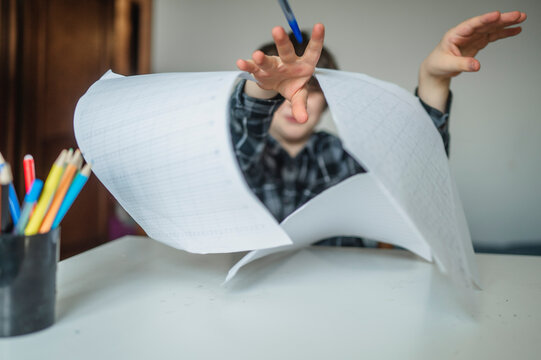 Frustrated schoolboy throwing paper while studying at home