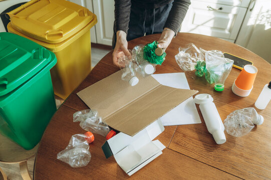 Hands sorting plastic and paper waste for recycling at home