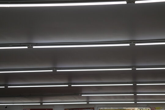 Fluorescent ceiling lights arranged in grid pattern, illuminating modern interior with bright, even lighting, ideal for office and commercial spaces